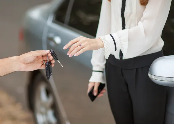 Männliche Hand übergibt Autoschlüssel an weibliche Hand. — Stockfoto