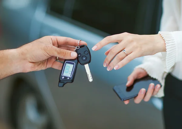 Männliche Hand übergibt Autoschlüssel an weibliche Hand. — Stockfoto