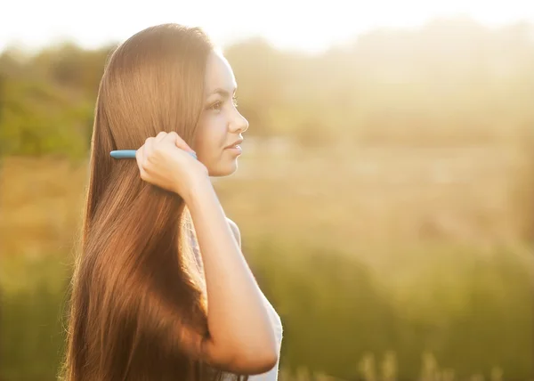 Beautiful girl combs her hair — Stock Photo, Image