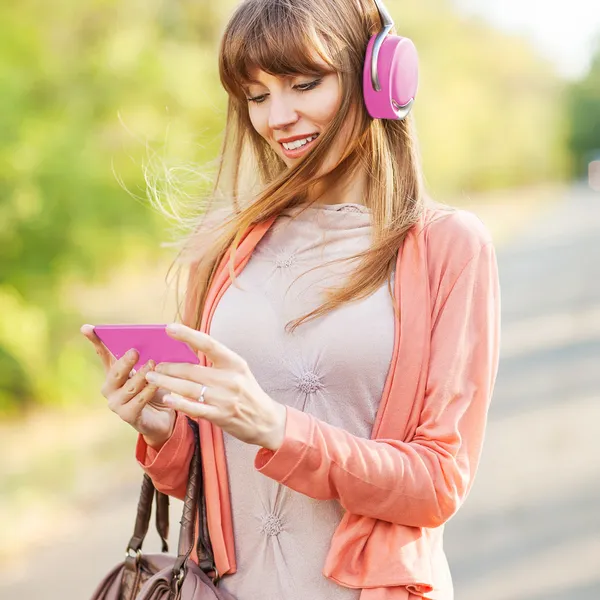 Young beautiful girl listening to MP3 player on the street — Stock Photo, Image