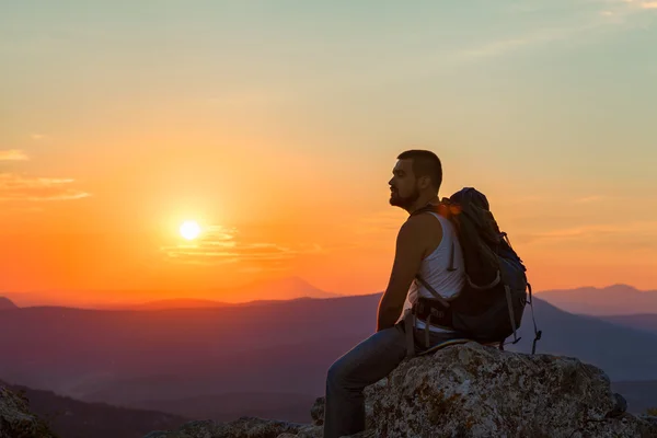 Tourist sits in the mountains enjoying the sunrise — Stock Photo, Image