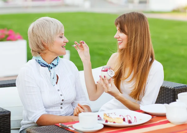 Senior Mutter und junge attraktive Tochter essen Kuchen, trinken — Stockfoto