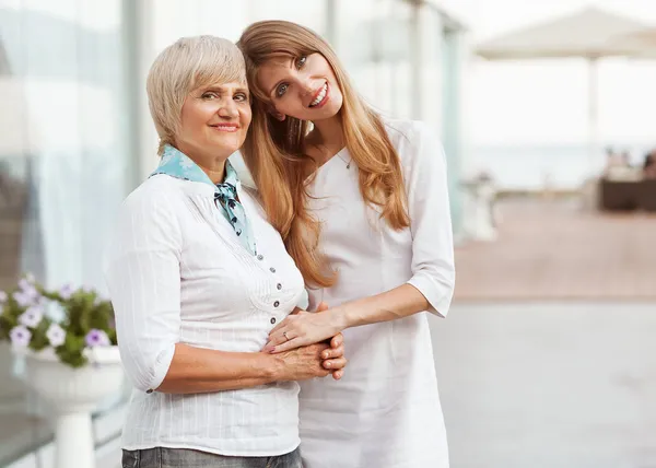 Vuxen mor och dotter står vid det stora glaset fallet holdi — Stockfoto