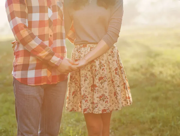 Heureux couple tenant la main regardant au coucher du soleil — Photo