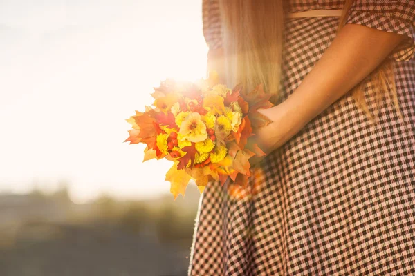 A young girl in a checkered dress with a bouquet in the sunshine — Stock Photo, Image