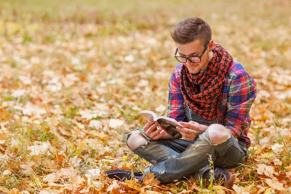 Young relaxed man reading book in nature, back on tree — Stock Photo, Image