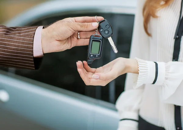 Männliche Hand übergibt Autoschlüssel an weibliche Hand. — Stockfoto