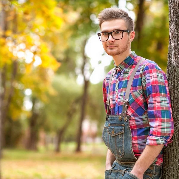 Hipster in piedi in autunno parco ghigno — Foto Stock