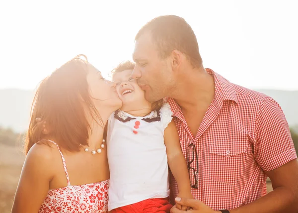Happy mother, father and daughter in sunset — Stock Photo, Image