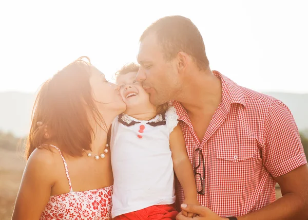 Happy mother, father and daughter in sunset Stock Image