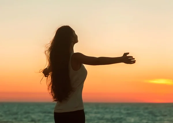 Freie Frau genießt Freiheit und fühlt sich glücklich am Strand bei Sonnenuntergang. — Stockfoto