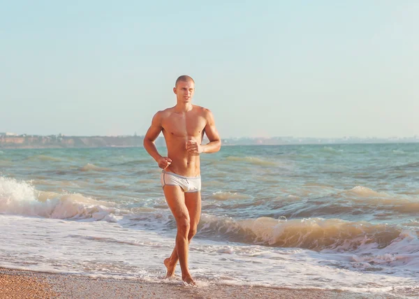 Sportler läuft am Strand — Stockfoto