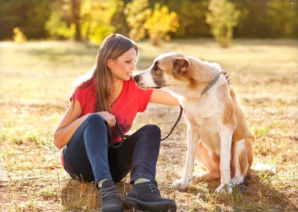 Portrait of a woman with her beautiful dog lying outdoors — Stock Photo, Image