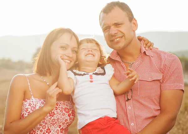 Happy mother, father and daughter in sunset — Stock Photo, Image