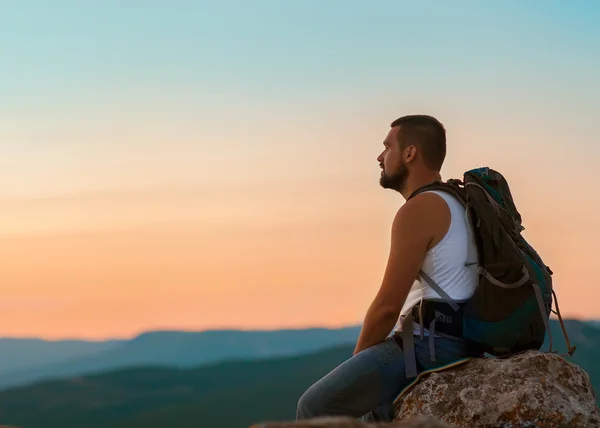 Um tipo nas montanhas ao pôr-do-sol. o conceito de liberdade — Fotografia de Stock