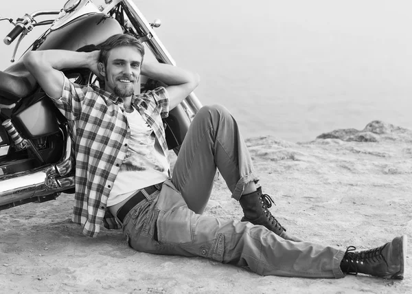 Adam bisikleti sırtı ile sahilde oturuyor. — Stok fotoğraf