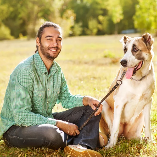 Man and central Asian shepherd walk in the park. He keeps the do — Stock Photo, Image
