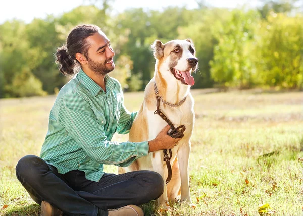 Mann und zentralasiatischer Schäferhund spazieren durch den Park. Er behält die Macht — Stockfoto