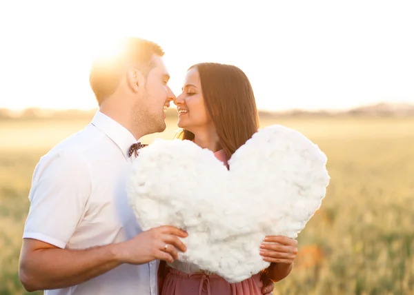 Young couple kissing behind heart cutout in the nature — Stock Photo, Image