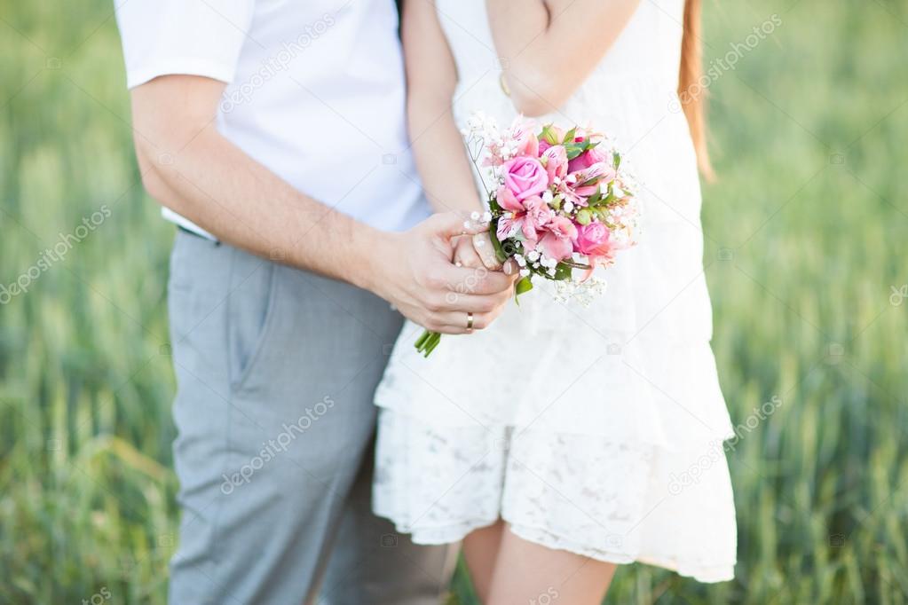 Young husband holding bride hands with bouquet