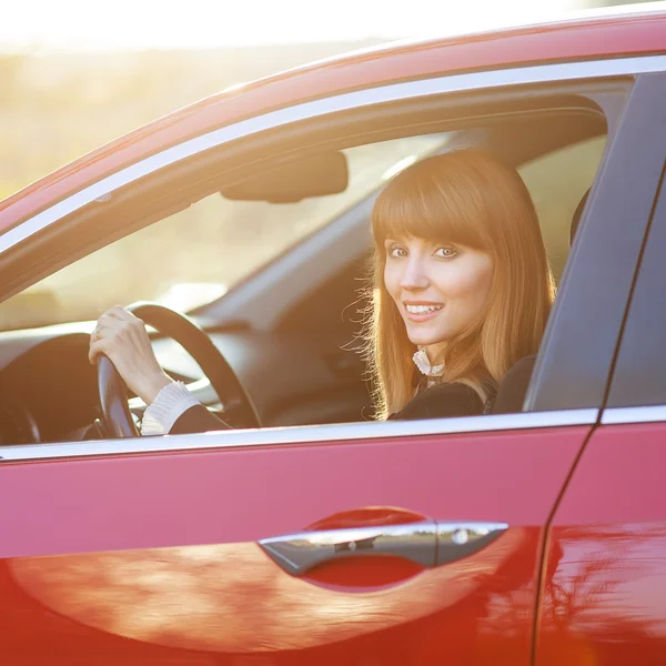 Pretty girl in a car at sunset — Stock Photo, Image