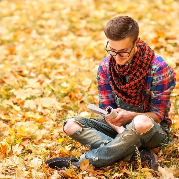 若いヒップなリラックスした男は、自然の中で本を読んで — ストック写真