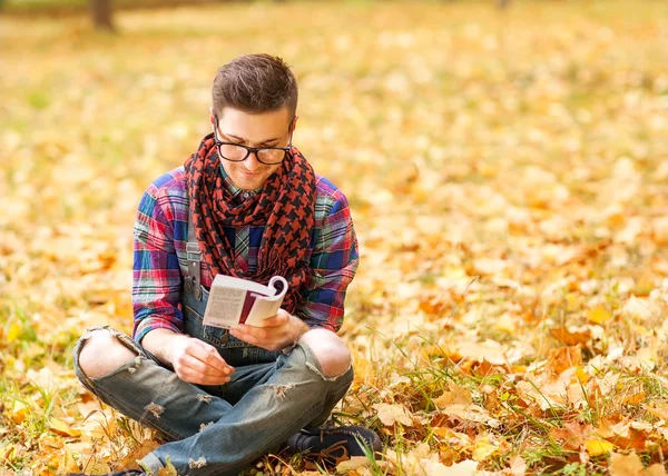 Jovem hipster relaxado homem leitura livro na natureza — Fotografia de Stock