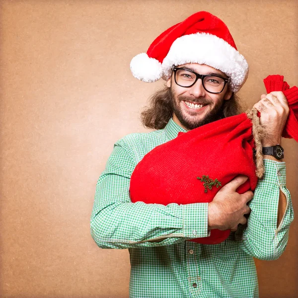 Weihnachtsmann mit einem Sack voller Geschenke blickt in die Kamera — Stockfoto