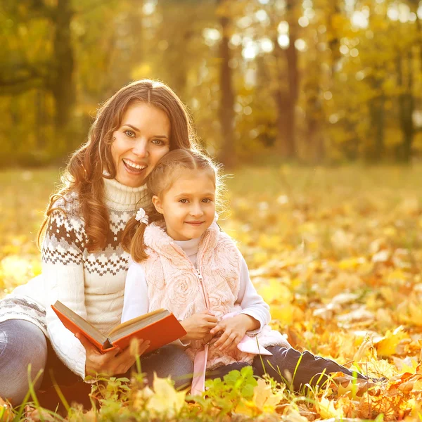 Moeder en dochter plezier in de herfst park onder de val — Stockfoto