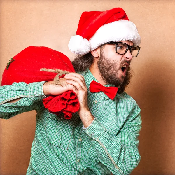 Hipster i santa claus kläder med påse med presenter — Stockfoto