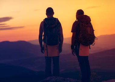 iki yürüyüşçü Sunrise bir dağın tepesinden tadını çıkarıyor.
