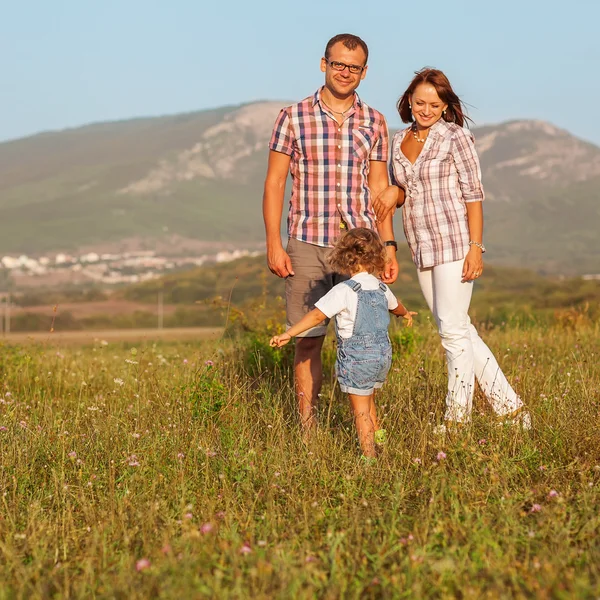 Father mother and daughter walking on the field — Stock Photo, Image