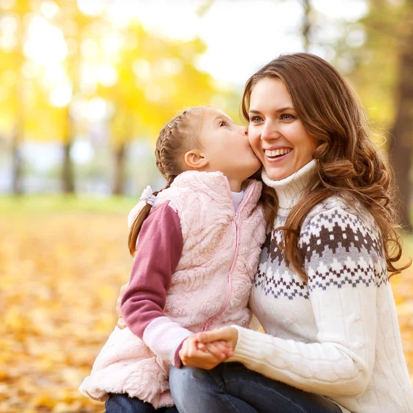 Mother and daughter having fun in the autumn park among the fall — Stock Photo, Image