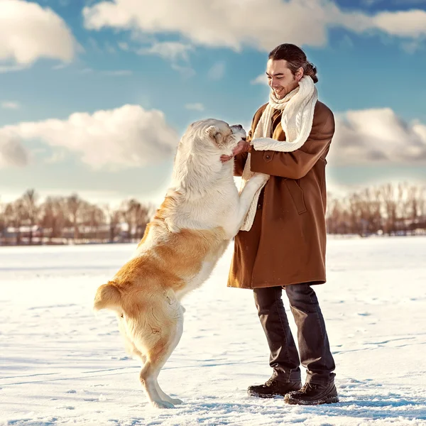 Man and central Asian shepherd playing with his dog outdoors — Stock Photo, Image