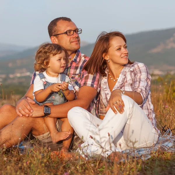 Mãe feliz, pai e filha no pôr do sol — Fotografia de Stock