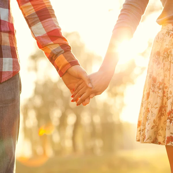 Young couple in love walking in the autumn park holding hands