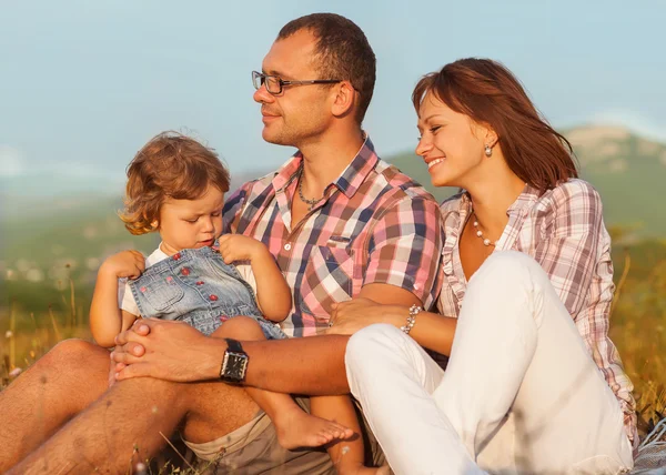 Glad mamma, pappa och dotter i solnedgången — Stockfoto