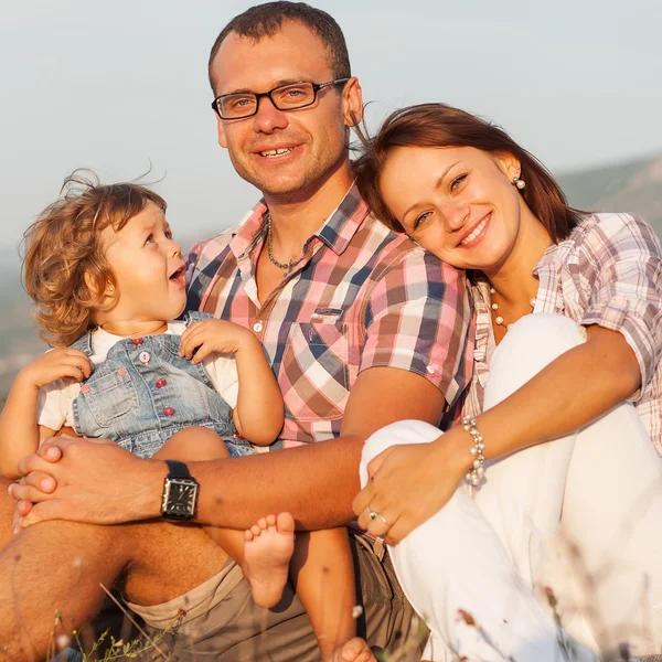 Mãe feliz, pai e filha no pôr do sol — Fotografia de Stock