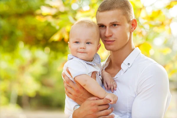 Joven feliz sosteniendo a un bebé sonriente de 7-9 meses —  Fotos de Stock