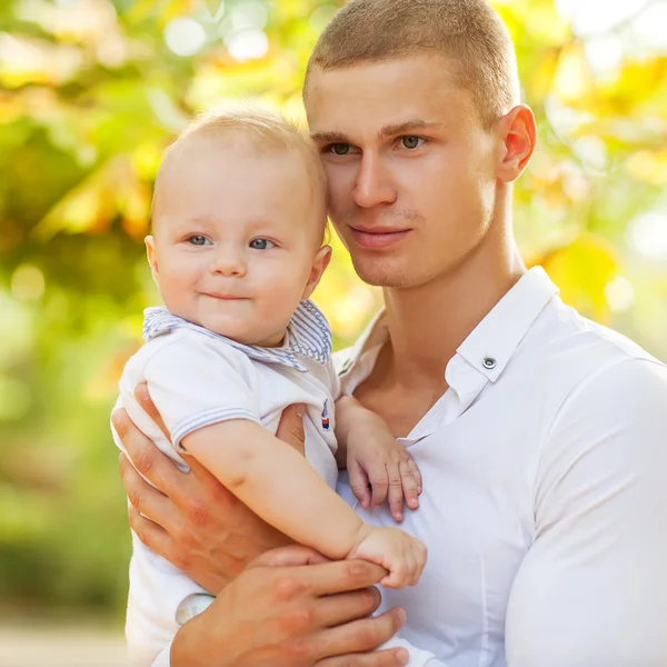 Glad ung man innehar en leende 7-9 månader gammal baby — Stockfoto