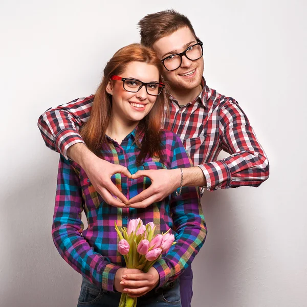 Young couple in love make a heart and hands are holding a bouquet of tulips — Stock Photo, Image