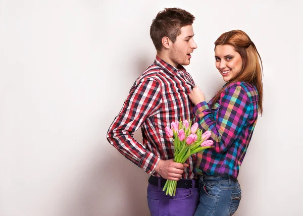 Jeune couple amoureux font un cœur et les mains tiennent un bouquet de tulipes — Photo