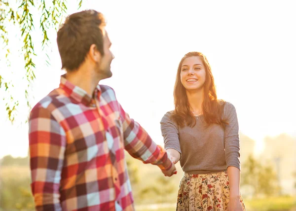 Pareja sosteniendo las manos caminando lejos, sonriendo — Foto de Stock