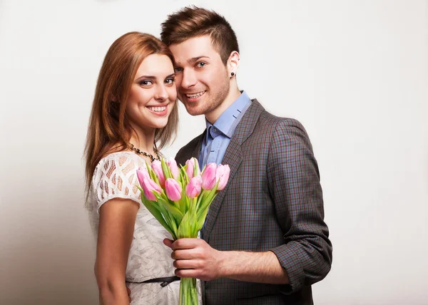 Pareja joven enamorada sosteniendo un ramo de tulipanes . —  Fotos de Stock