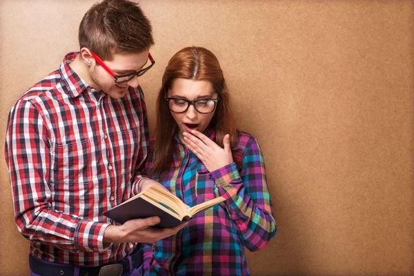 Young couple in clothes and stylish hipster glasses reading a book. — Stock Photo, Image