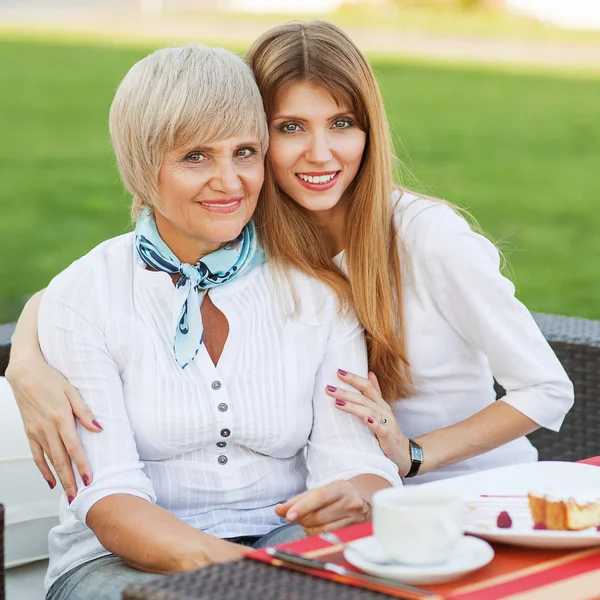 Adult mother and daughter drinking tea or coffee and talking outdoors. — Stock Photo, Image