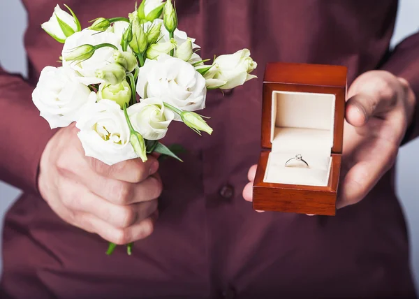 Holding ring box and a bouquet of flowers — Stock Photo, Image