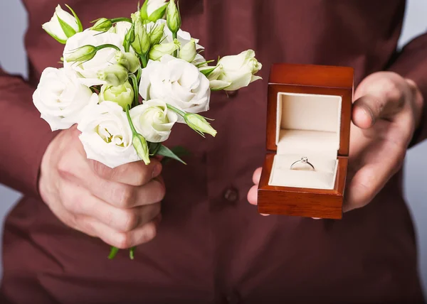 Holding ring box and a bouquet of flowers — Stock Photo, Image