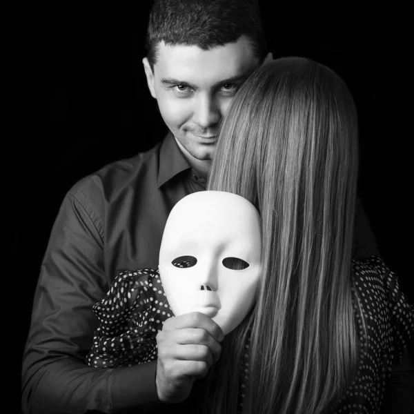 Moda feliz pareja en el amor sosteniendo una cara de máscara blanca . — Foto de Stock