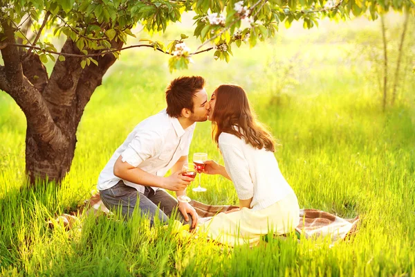 Casal apaixonado beijando na natureza estão segurando copos de vinho — Fotografia de Stock